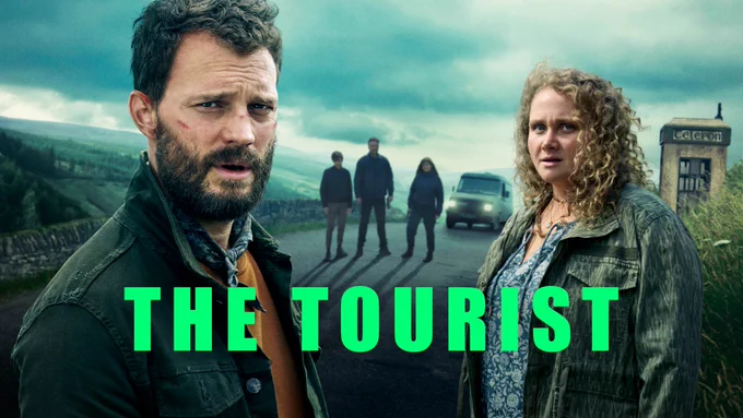 Key art for The Tourist series two featuring Jamie Dornan and Danielle Macdonald looking to camera as they stand on a remote country road. Three unidentifiable figures are stood in the background next to a truck. 
