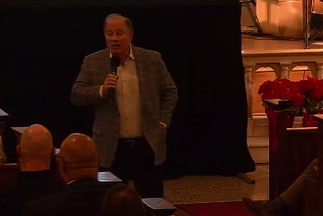 Detroit Mayor Mike Duggan with a microphone speaking at a community meeting