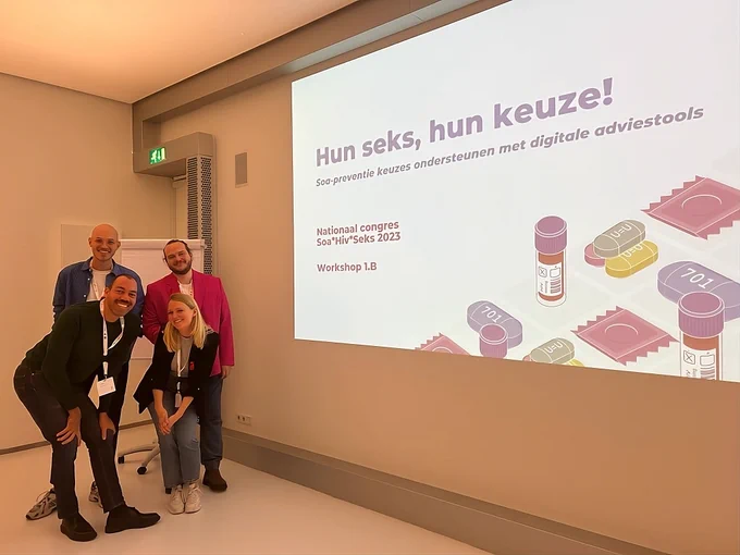 Four happy individuals stand together in front of a presentation with the empowering title 'Hun seks, hun keuze!' (Their sex, their choice!). 