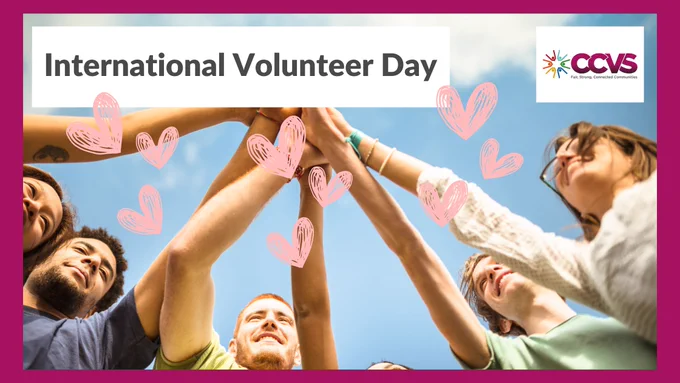 A group of people with their hands in the air, hearts floating in the background. International Volunteer Day