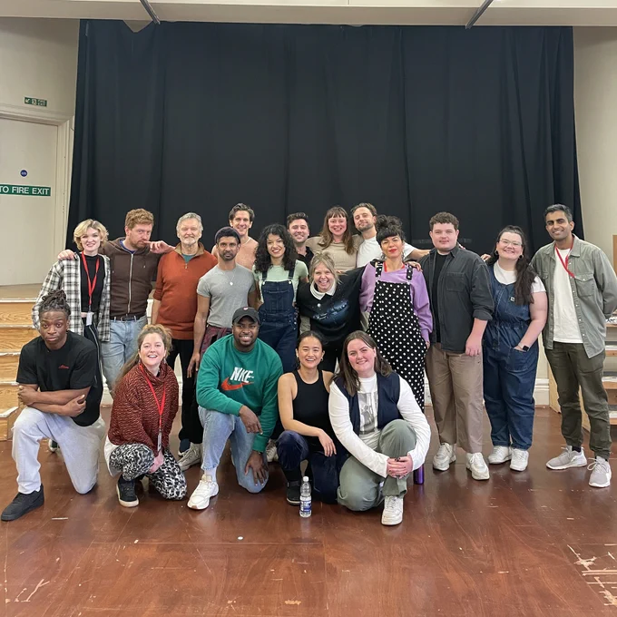 The cast of A Midsummer Night's Dream in the rehearsal room. Five people are kneeling in front with everyone else standing behind.
