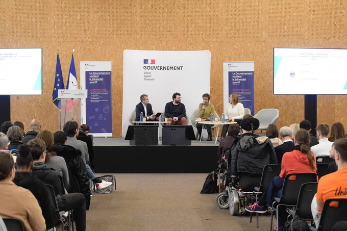 Au premier plan, à gauche et à droite des personnes de dos écoutent les intervenants sur la scène. 
Au second plan, quatre intervenants installés sur l’estrade échangent dans le cadre de la deuxième table ronde sur les programmes « Dirigeants de demain » et « Club des 300 » du CNOSF