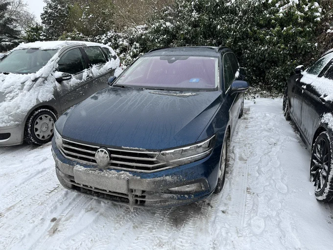 Ein Auto mit durch Schnee unlesbarem Nummernschild vorne.