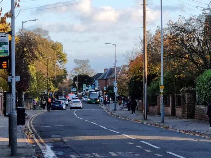 Image of a road into West Bridgford with cars parked down one side and a bus passing on the other