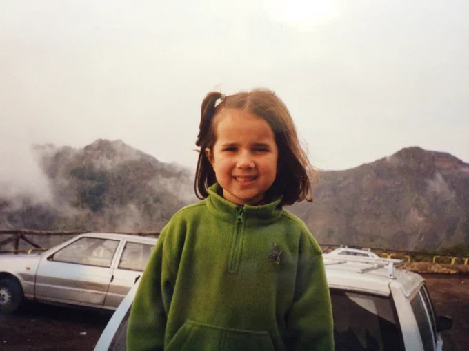 old photograph of young girl in front of volcanic crater