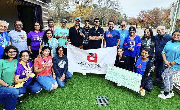 The Active Desi team gathers with Para Guide outdoors with a large presentation check