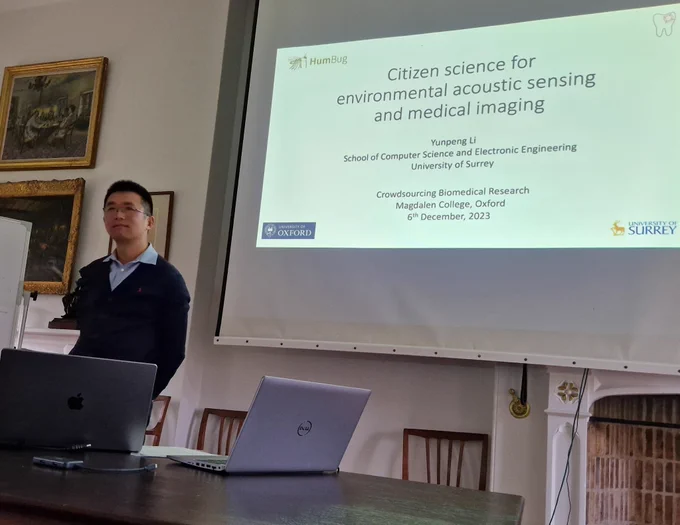 Researcher standing in front of a screen with a slide titled "Citizen science for environmental acoustic sensing and medical imaging"