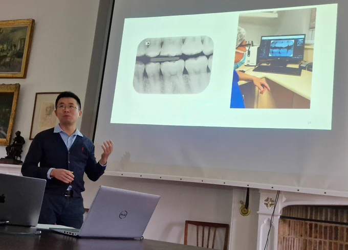 Researcher standing in front of a screen showing dental x-rays