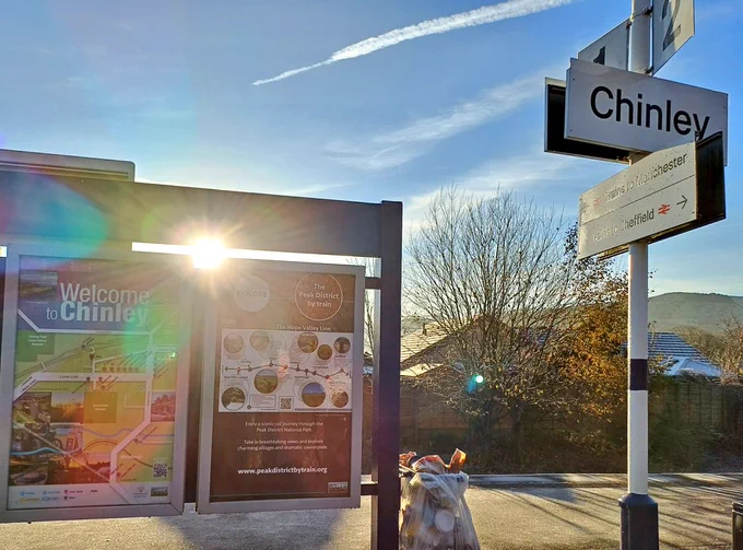 Chinley station in the sun with signs on the platform 