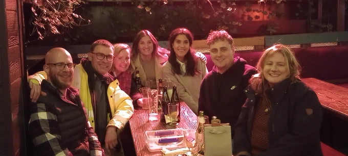 Group of people at a table, smiling at the camera. 