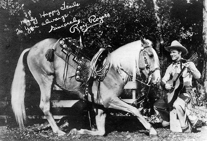 Roy Rogers with guitar next to Trigger