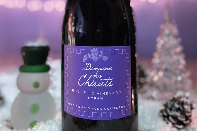 A magnum of Jeff Cohn Cellars Domaine des Chirats Syrah on a festive holiday table with a frosted glass snowman and a glass tree.
