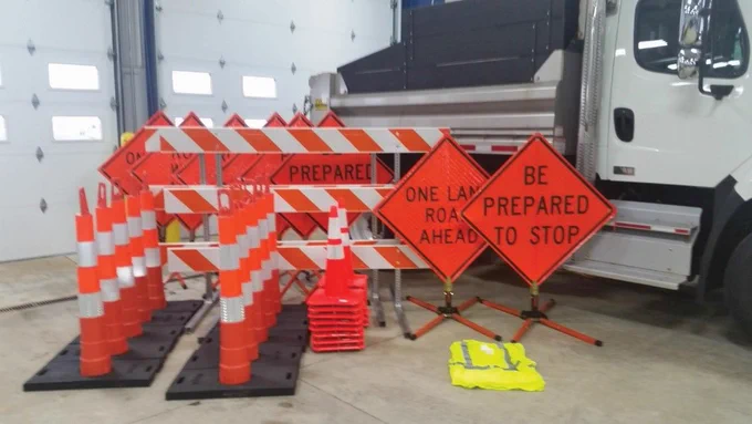 Work zone equipment that includes cones and signs as well as a protective vest at a maintenance garage