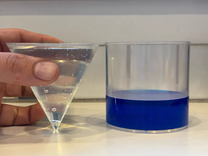 The second photo in the sequence. The cylinder is now 1/3 full of the blue liquid and the cone is filled with a thick, clear syrup (Karo).