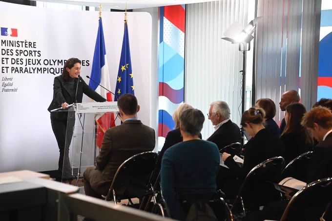 Photo de la ministre debout, derrière un pupitre, s’adressant au public assis.
