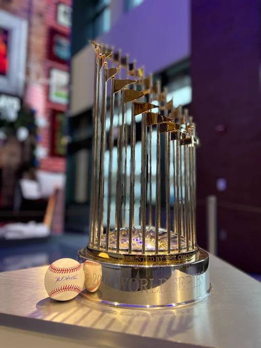 A Kyle Hendricks signed baseball rests next to the Cubs 2016 World Series trophy.