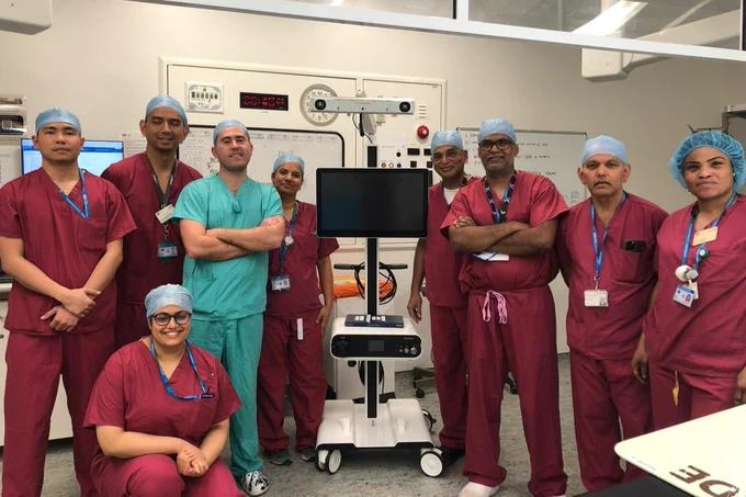 Team photo of Imperial College Healthcare and London North West University Healthcare staff dressed in theatre uniform and scrubs and standing for a team photo.