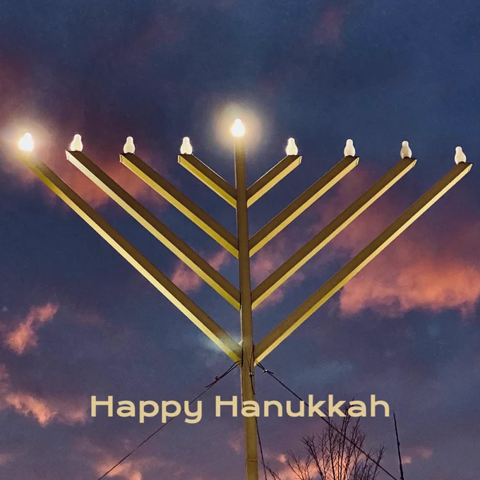 A menorah lit for the first night of Hanukkah with the sunset clouds in the background.