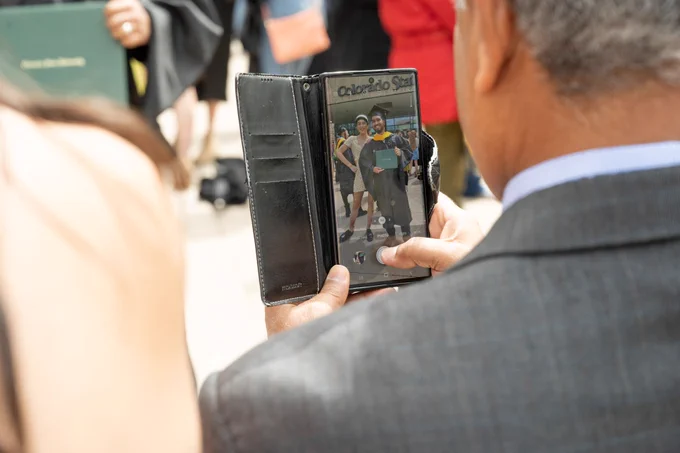 A man takes a photo of someone in graduating from college.