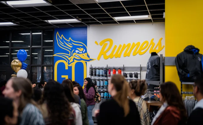 Go `Runners wall in focus with people wandering in front in CSUB Bookstore