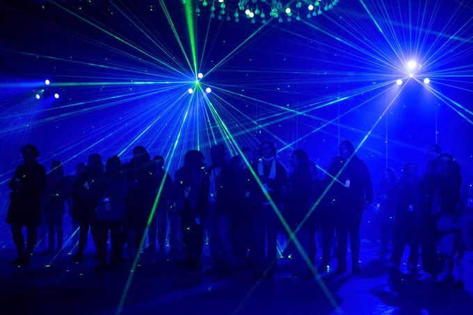 Silhouettes of people stood in the dark with lasers around them.