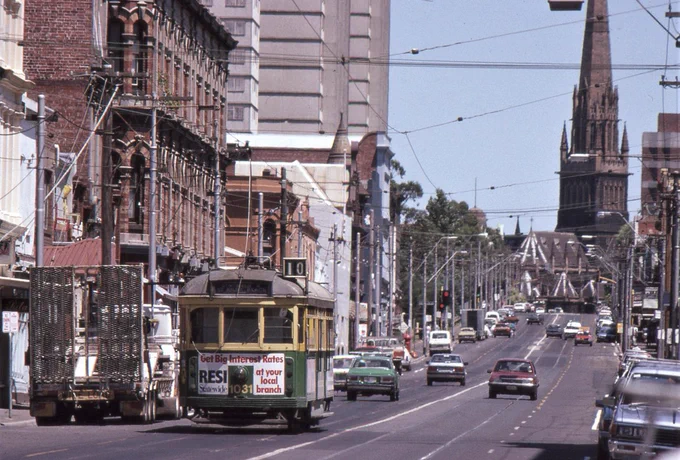 A W7 class tram runs along Brunswick Street Fitzroy with the spire of St Patrick’s cathedral providing a spectacular terminated vista at the end of the street.