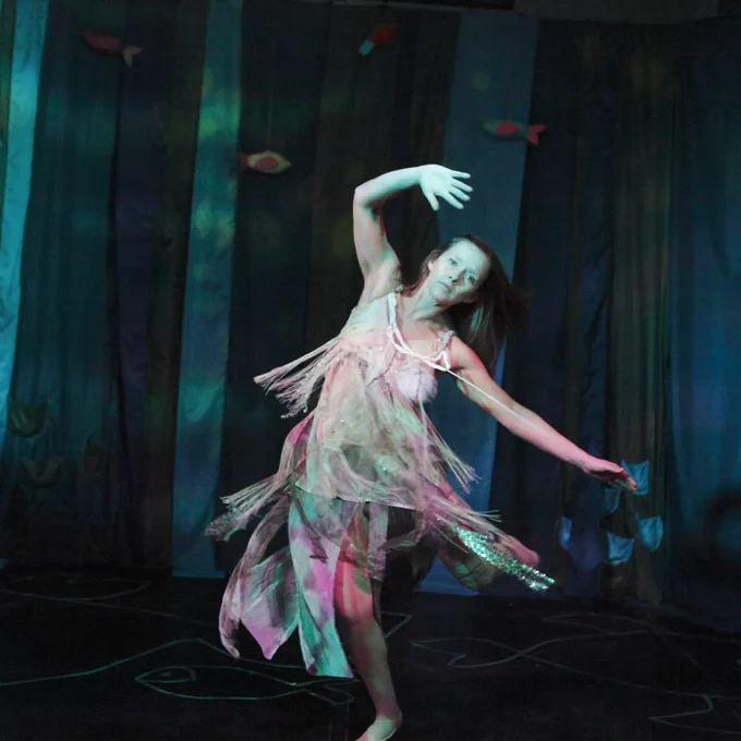 Nina dances ethereally as the fairy with her arm teaching over head as she spins. Here costume tassels spin out.