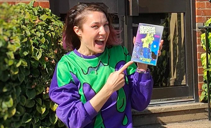 Bec Hill happily holding up a copy of her furst Horror Heights book