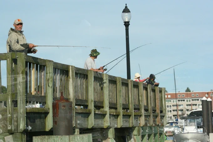 Saltwater anglers fishing from a city pier.
