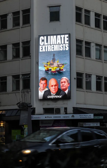 Christopher Luxon, David Seymour and Winston Peters are labelled as climate extremists on a billboard in Wellington with an offshore oil rig.
