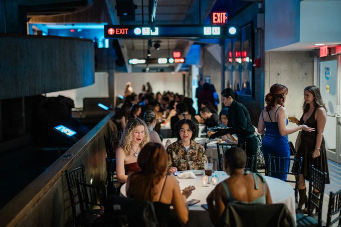 People chat at tables and while standing inside an aquarium.