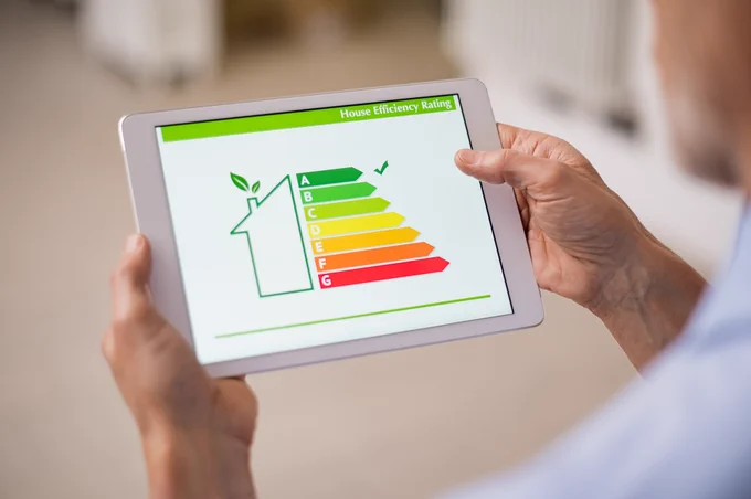 a person's hands holding a tablet with a home's energy efficiency rating shown on the screen
