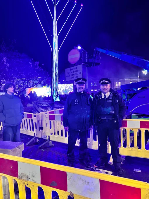 Officer stands with a member of the public at a Menorah Lighting ceremony. 