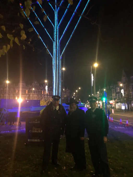 Officer stands with a member of the public at a Menorah Lighting ceremony. 