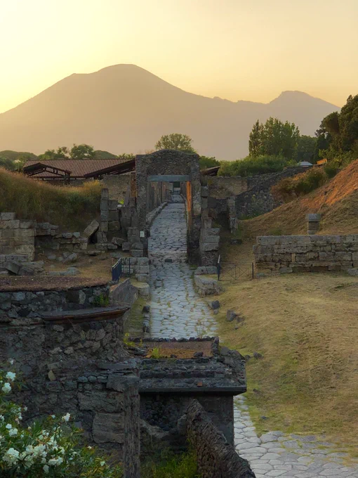 A view up the Roman road that runs under the Nocera Gate at the end of the day when the light is warm and Vesuvius looms in the background in silhouette against the orange sky