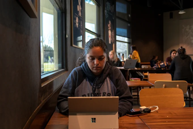 Student sitting at table in Starbucks working on laptop