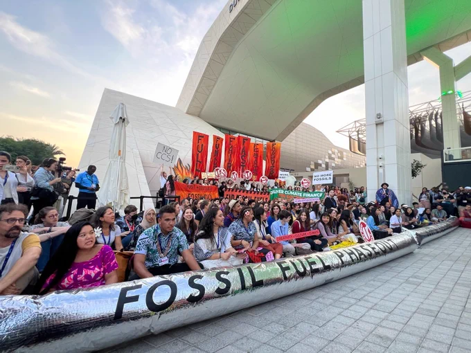 Protestors stand in front of long banner that says 'Fossil fuel phaseout'