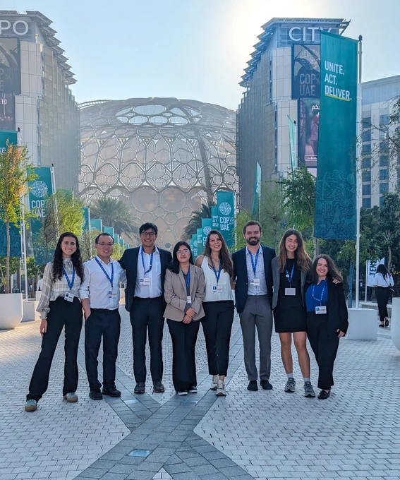 Students near the front of the event with COP 28 signs and large structure behind them
