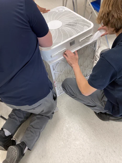 Photograph of 2 students adding more duct tape to our almost-finished CR box