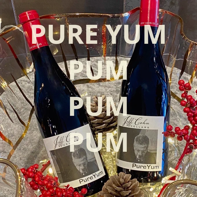 Two bottles of  2018 Jeff Cohn Cellars Pure yum in a glass  bowl with fairly lights, pinecones and red berries.