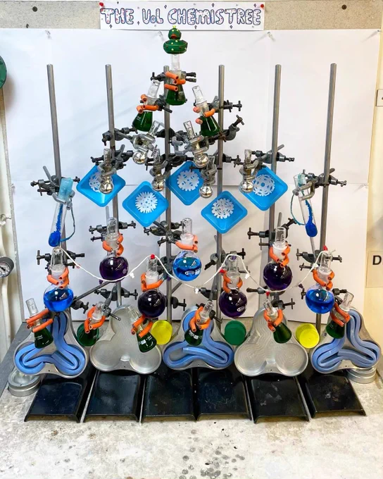 Retort stands supporting colourful liquids in round bottom flasks and conical flasks, filter papers in weighing boats and a Christmas themed duck at the top of the tree