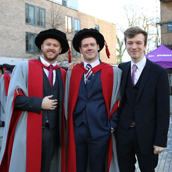 Photo three people, two with graduation robes