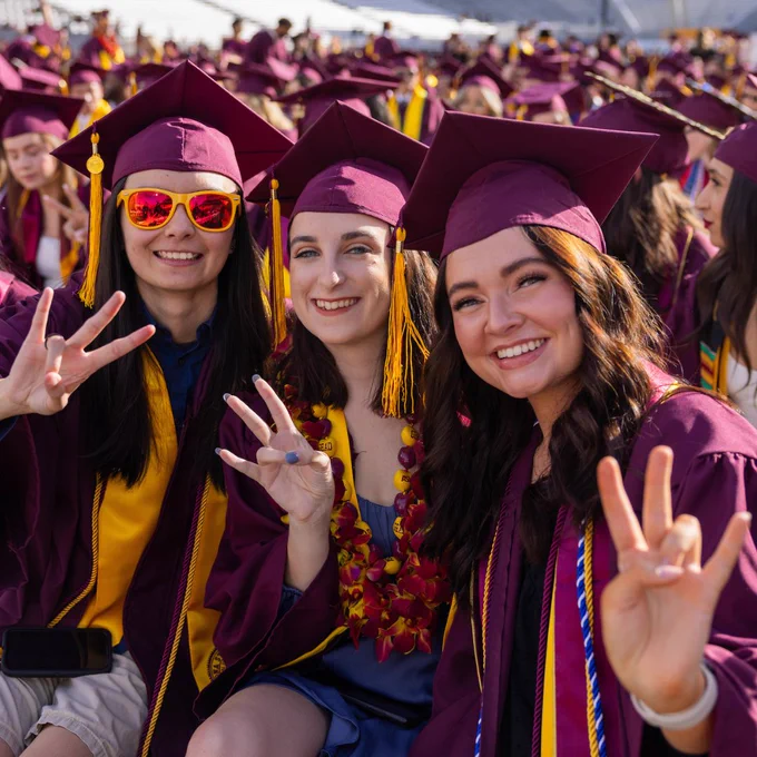 Three graduating students make the Pitchfork sign during ASU's undergraduate commencement