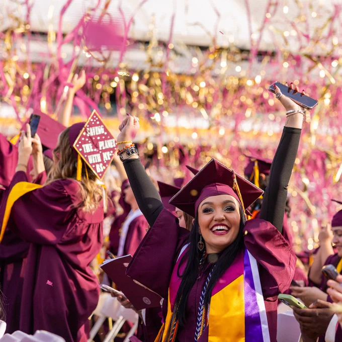 Student raises her hands in victory after ASU's undergraduate commencement ceremony