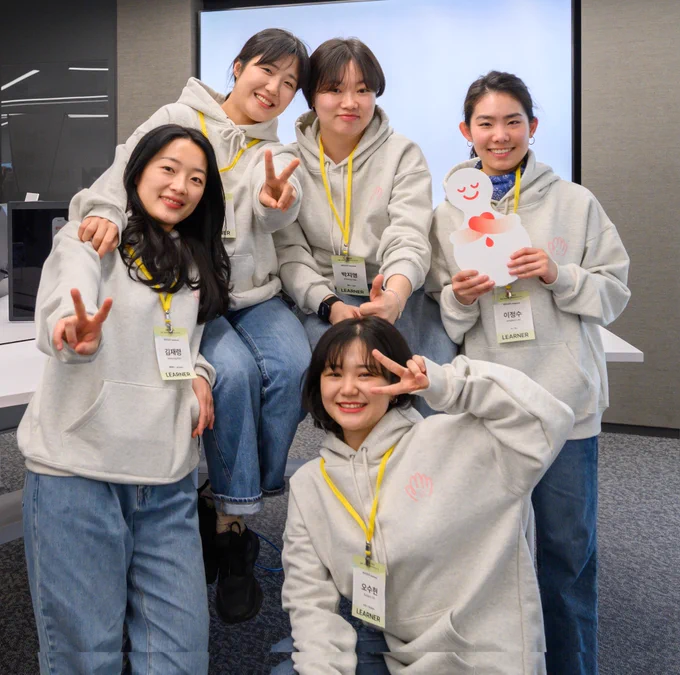 A group of students in Korea posing and smiling together, looking directly at the camera. 
