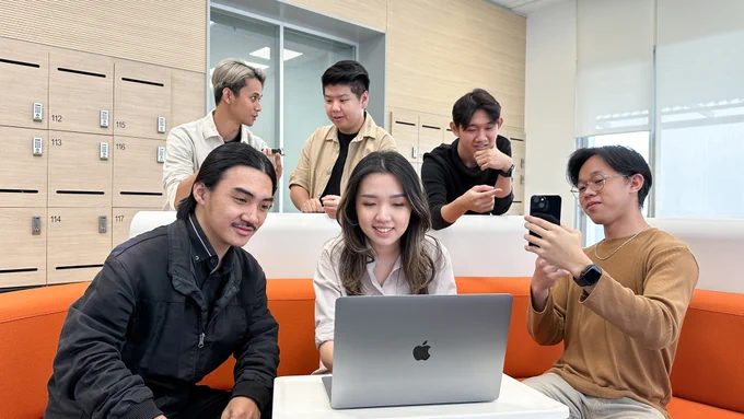 A group of six students working together in Indonesia on a MacBook and iPhone. 