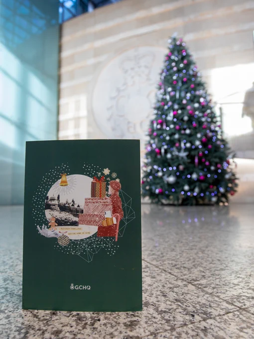 The 2023 GCHQ Christmas card in front of a Christmas tree inside GCHQ's headquarters