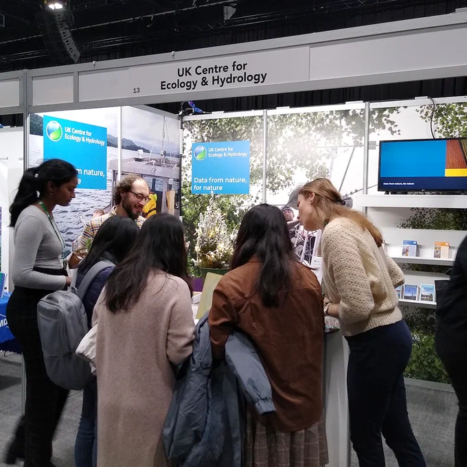 Six people looking at something on an exhibition stand