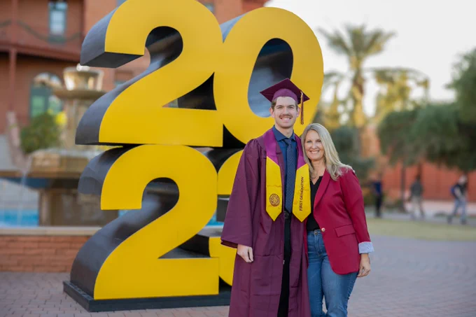 Graduate posing with his mom in front of 2023 sculpture. 