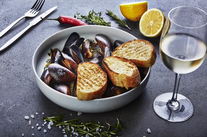 Moules mariniere with bread and glass of wine
